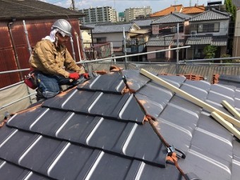 木の下地を組んだ屋根に瓦を並べる様子