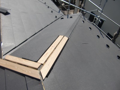 屋根の継ぎ目に垂木と棟板金を被せる様子