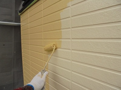 外壁に下塗り材塗装後、塗料本材を塗る様子