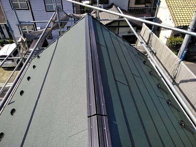 コケの生えたカラーベスト屋根のカバー工事の屋根材施工の様子