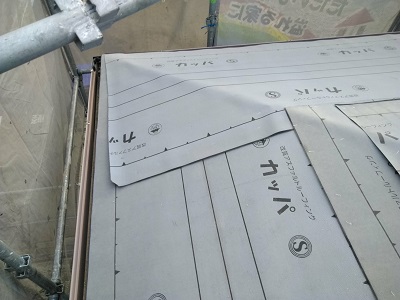 カラーベストの割れがある屋根の重ね葺き工事の防水シート施工中の様子