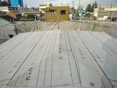 カラーベストの割れがある屋根の重ね葺き工事の防水シート施工中の様子